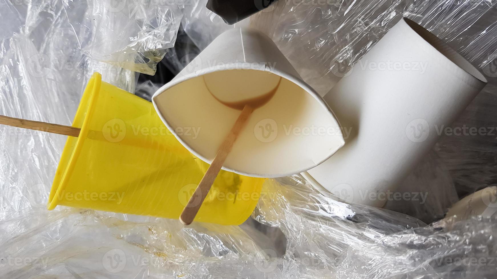 The concept of environmental issues. Uncomposted waste. Different types of waste are collected in containers for disposal. White coffee cup with a wooden coffee spoon used in a trash can with plastic. photo