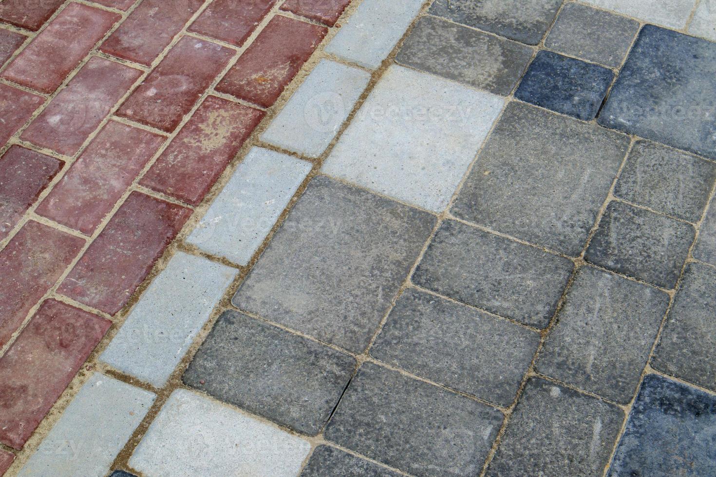 Concrete or paved newly laid gray and red paving slabs or stones for floors or walkways. Concrete paving slabs in the backyard or road paving. Garden brick path in the courtyard on a sandy foundation. photo