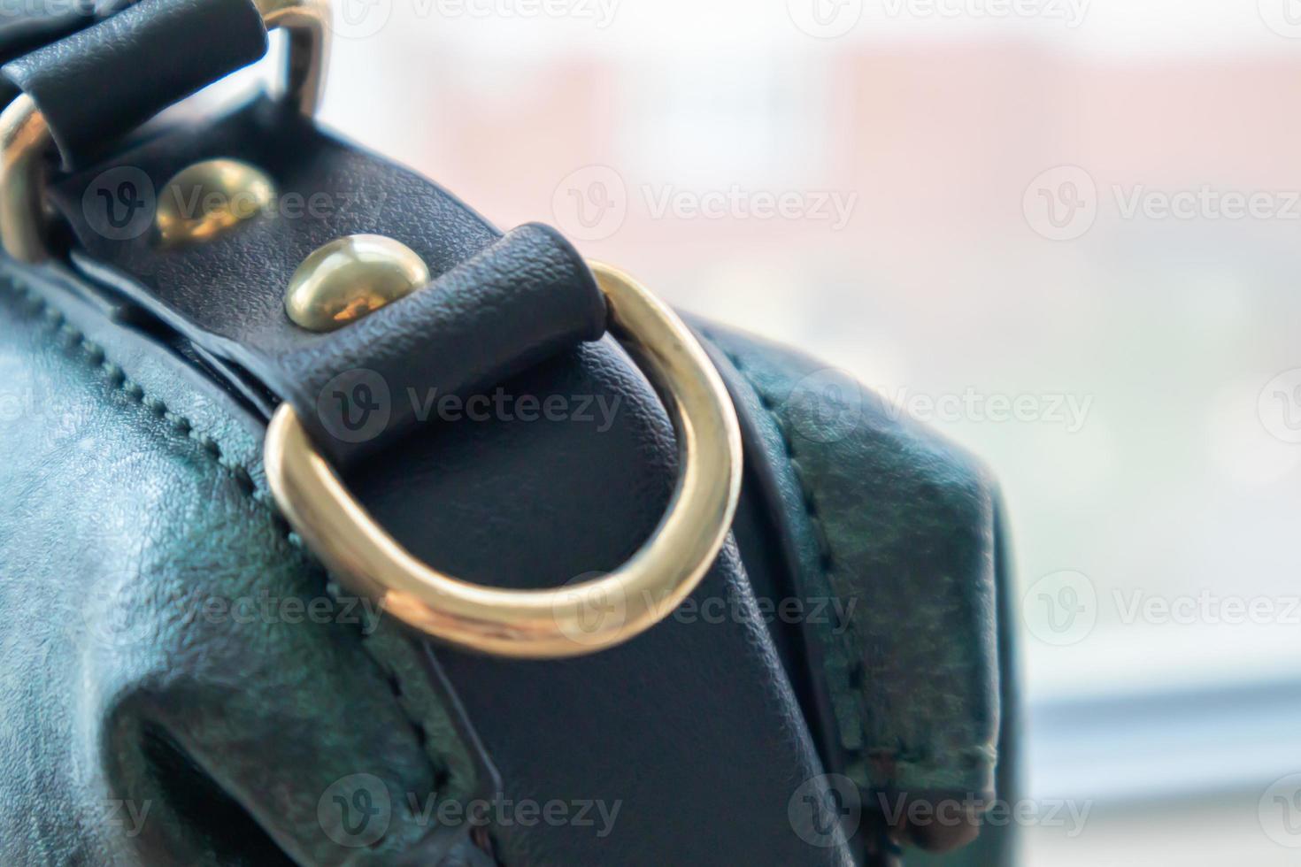 Metal gold loop oval ring attached to a leather bag. Selective focus. Part for a secure connection between two objects. Sewing accessories in the form of a ring for sewing bags, glossy. photo