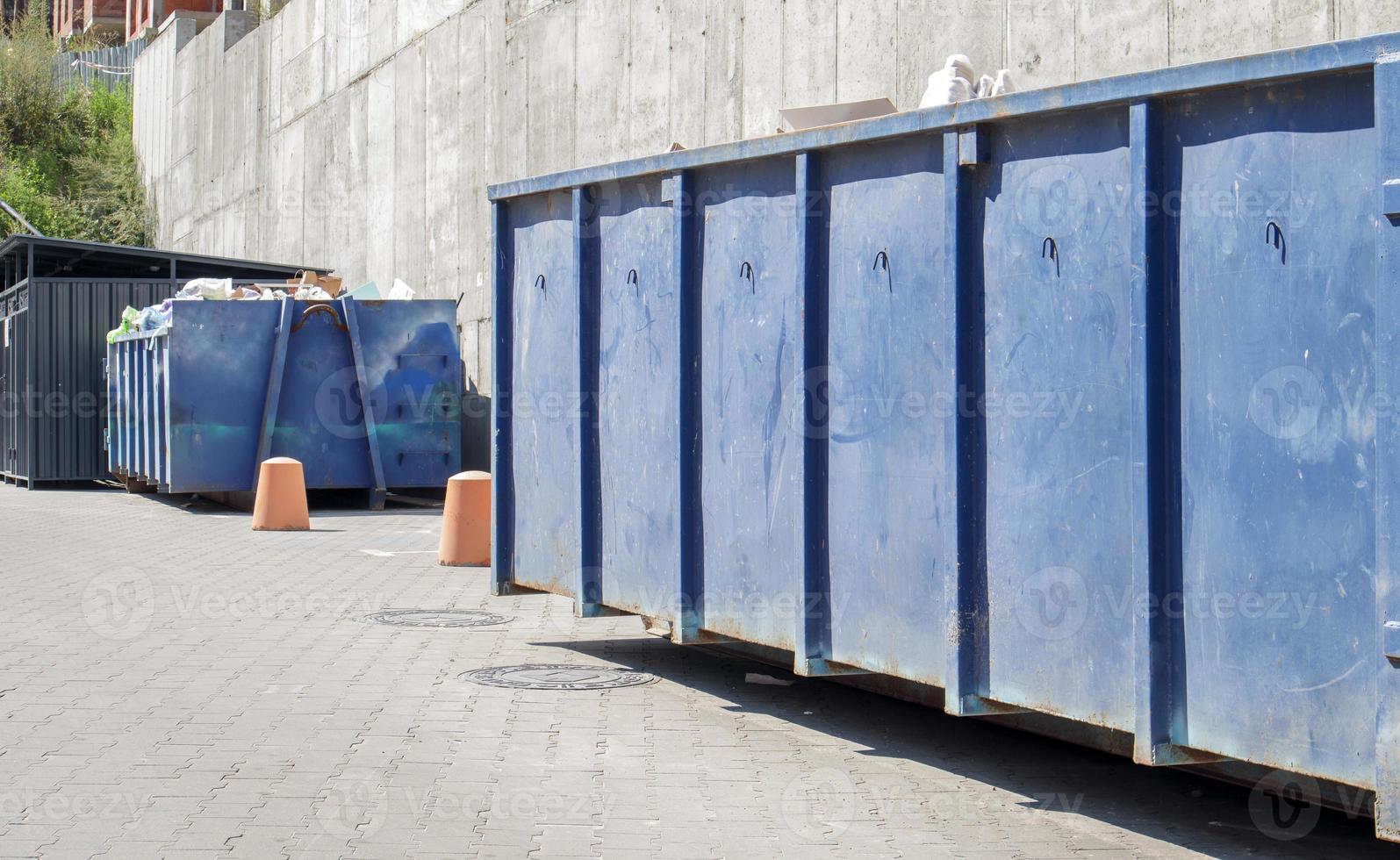 Cubo de basura industrial azul duradero de metal para basura al aire libre en el sitio de construcción. Gran papelera para residuos domésticos o industriales. un montón de basura. foto