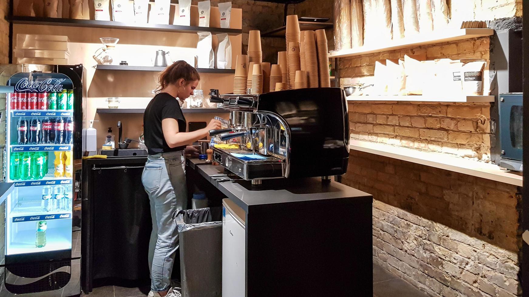 Ukraine, Kiev - March 06, 2020. Prepare a work order concept. Barista girl makes coffee. Cafe and counter with coffee equipment, espresso coffee machine, coffee grinder, cups for making drinks. photo