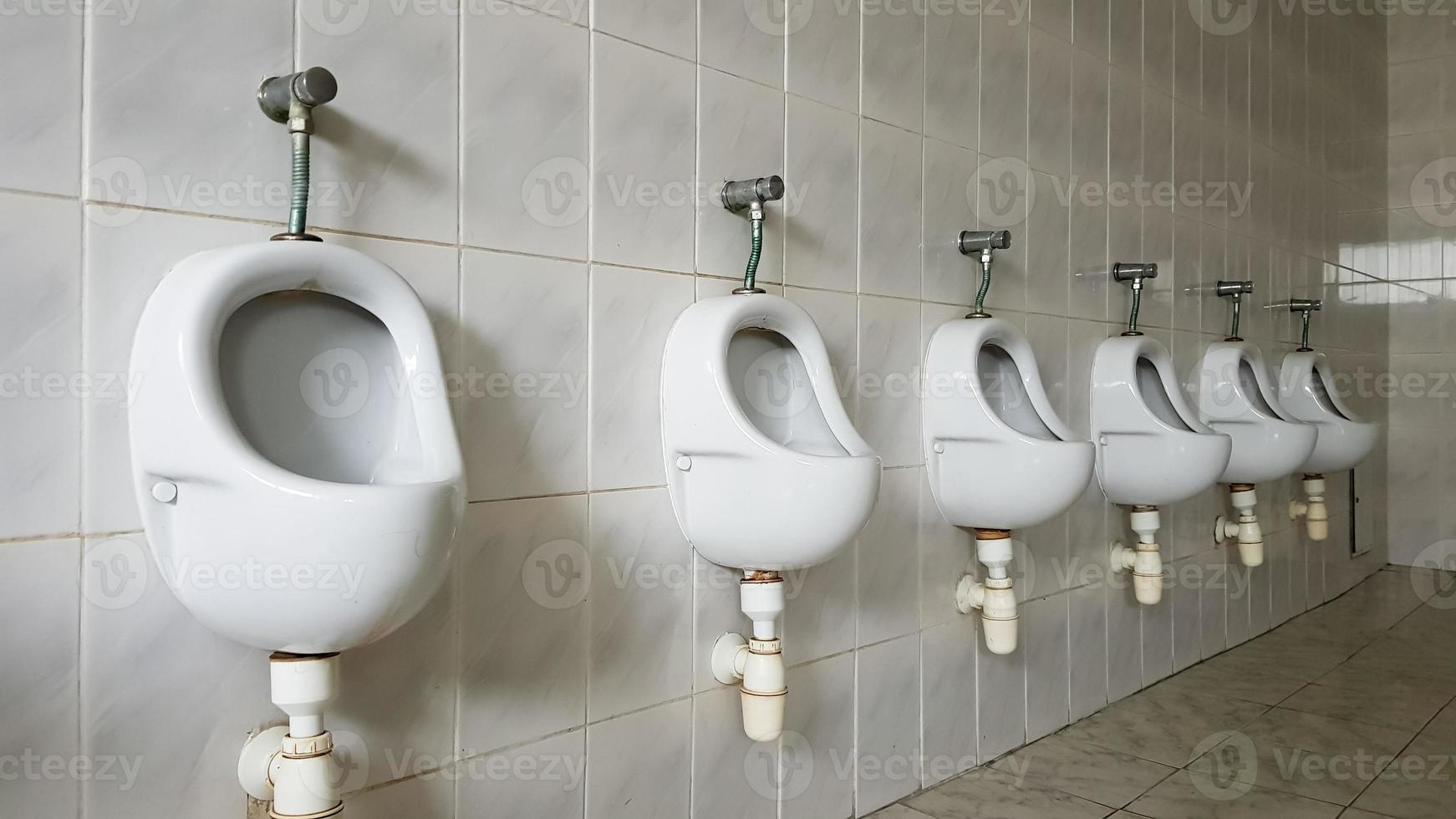 Public toilets with lots of ceramic urinals. Large public toilet, wall mounted bowls in the toilet. Urinals prepare bowls for men. photo