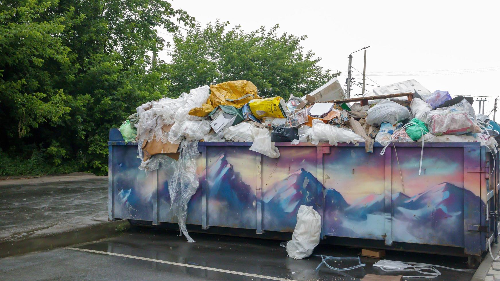 Metal durable blue industrial trash bin for outdoor trash at construction site. Large waste basket for household or industrial waste. A pile of waste. Ukraine, Kiev - August 09, 2021. photo