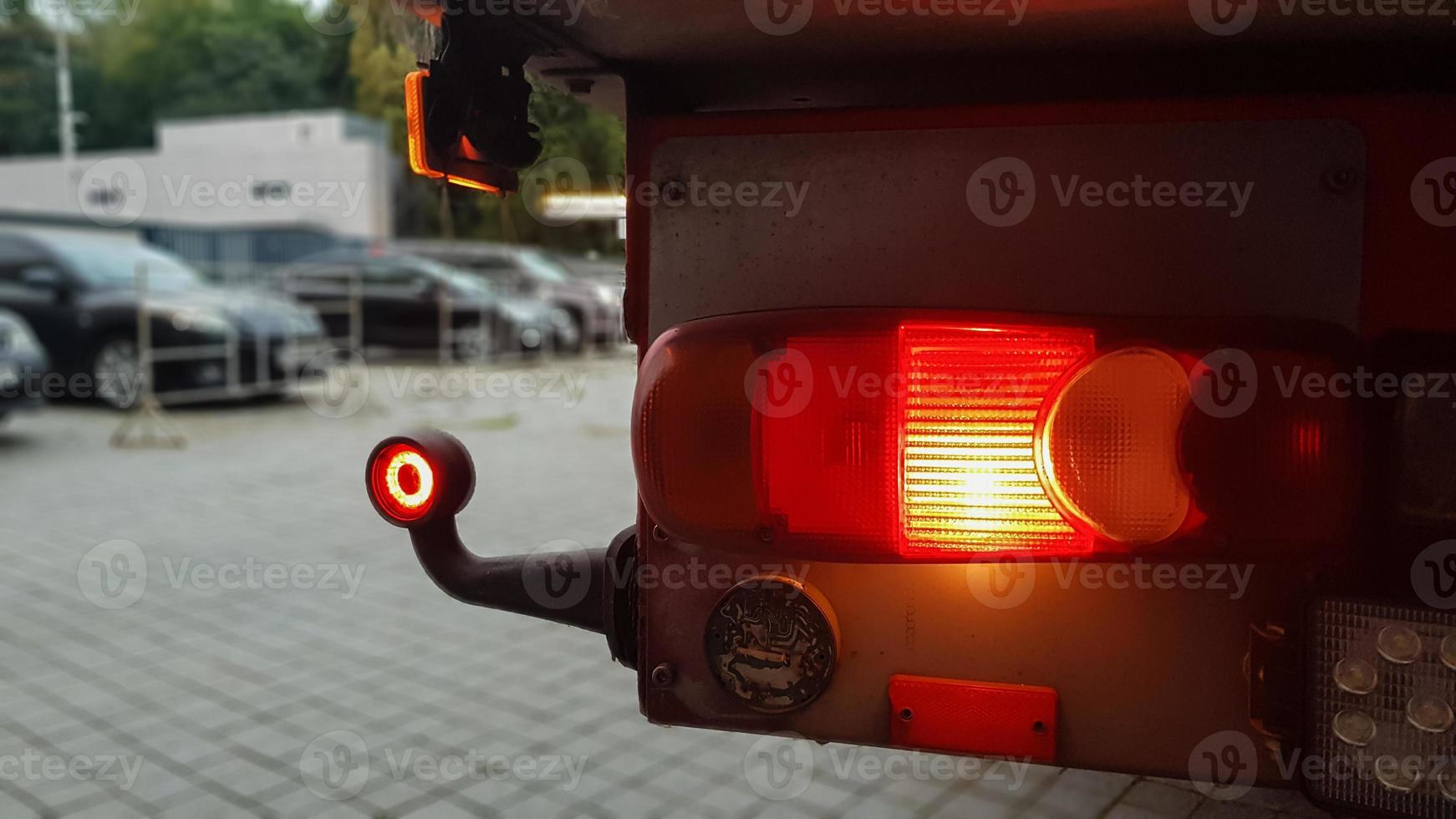 Close-up shot of the rear round red marker light of a truck. Rear light for a truck. The background is blurred. The concept of safe travel on the road at night. photo