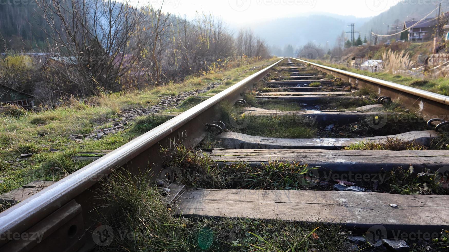 Cerrar vista en perspectiva de las vías del tren en un día soleado. barandillas y traviesas de madera en aceite con piedra triturada. Vista baja de rieles de acero de metal de transporte de trenes ferroviarios. foto