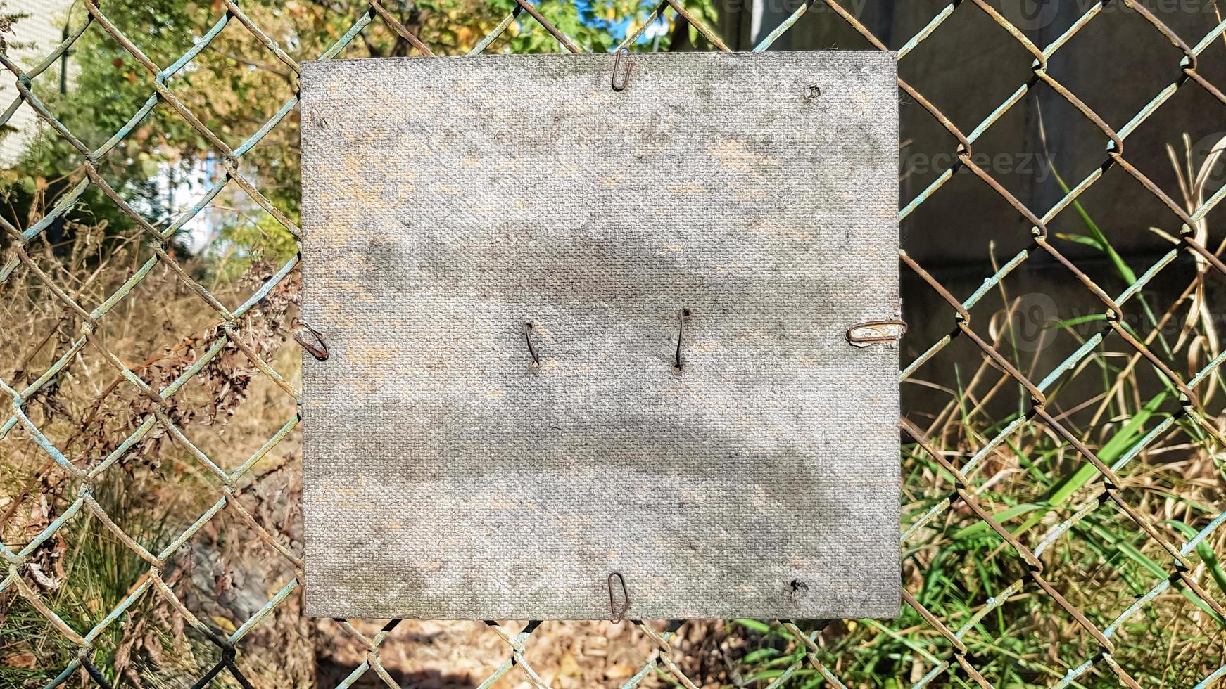 Old cracked square wooden plate on an old metal mesh. Place for your text or logo. Copy space photo