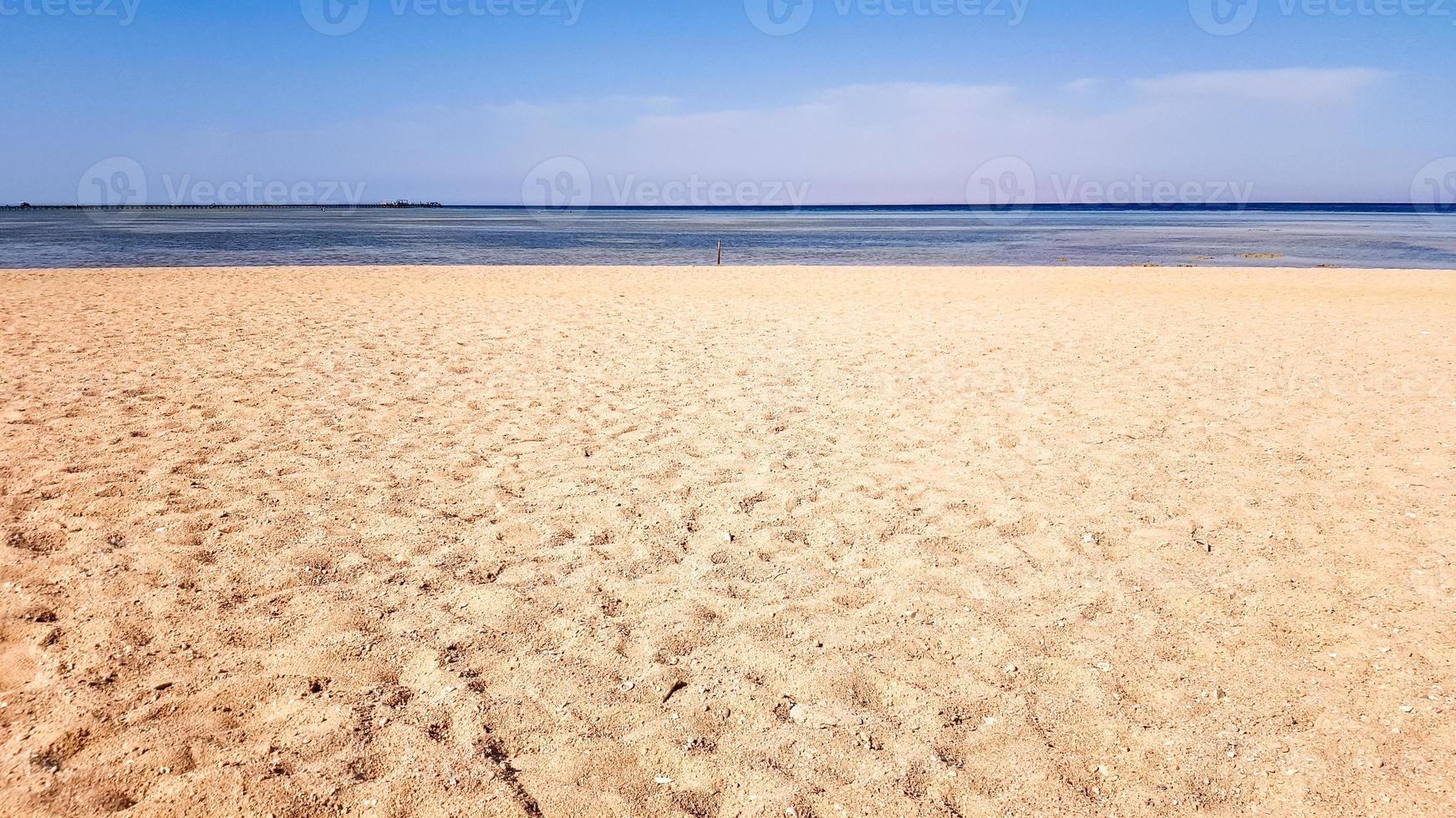 A beautiful sandy beach without people and a tropical blue sea with blue sky background. photo