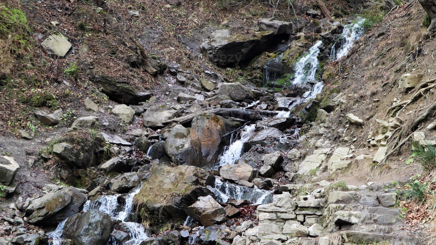 Waterfalls in a small canyon with stone walls. Beautiful cascade in the mountains. river in the Carpathians in the mountain autumn forest. scenic view, the movement of water. photo