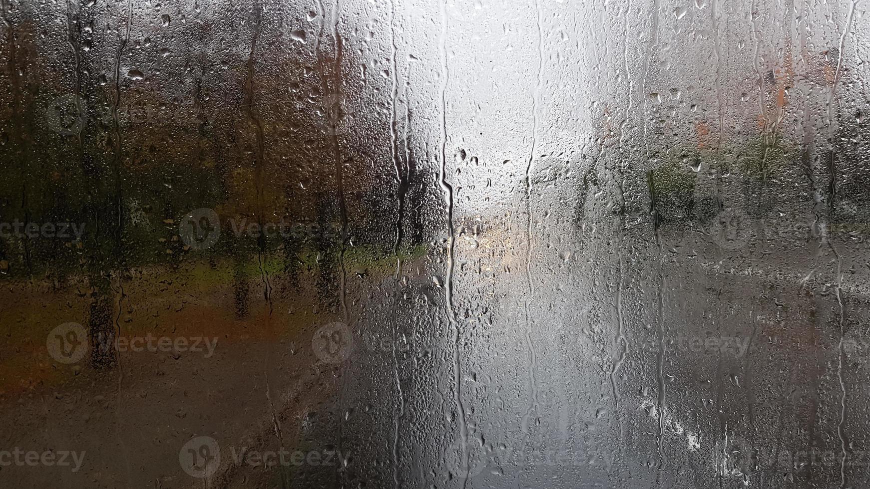 Rain on the rear window of a car in autumn. Inside view of the road with moving cars in the city through the window from the car with rain drops. driving a car in the field of view of the rear window. photo