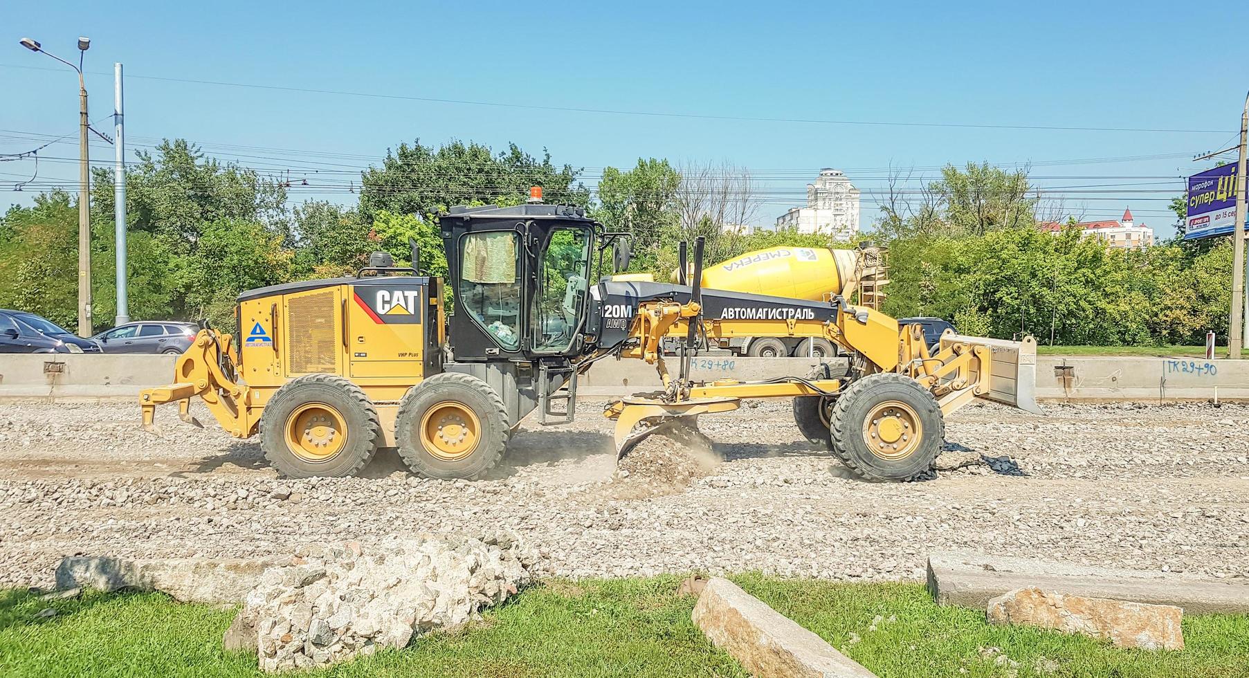 Ukraine, Kiev - October 1, 2019. Road roller, tractor and construction equipment are working on a new road construction site. The road is closed for road repair, route extension, pothole repair photo