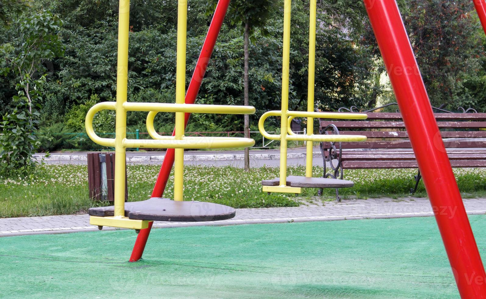 Patio de recreo moderno cerrado. Medidas de seguridad y protección contra el covid-19 en el parque de la ciudad. Bebé vacío columpio de metal amarillo en el parque sin gente. se acabó el concepto de infancia. foto