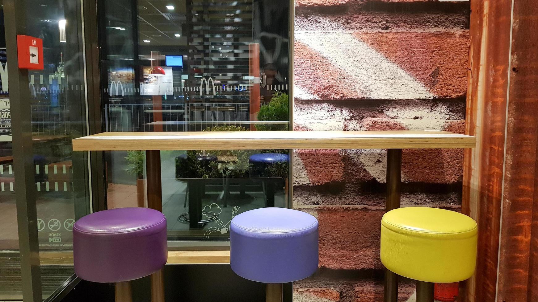 Ukraine, Kiev - August 19, 2019. McDonald's restaurant interior. McDonald's is the world's largest fast food restaurant chain based in the USA. Interior with tall tables and colored bar stools photo