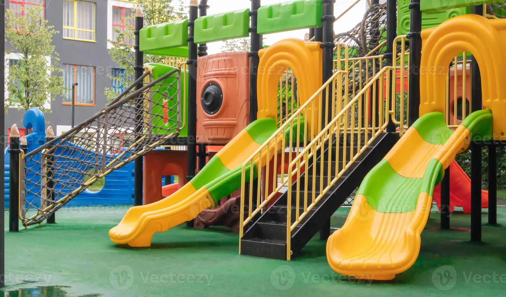 A courtyard of high-rise buildings with a new modern colorful and large playground on a rainy summer day without people. Empty outdoor playground. A place for children's games and sports. photo
