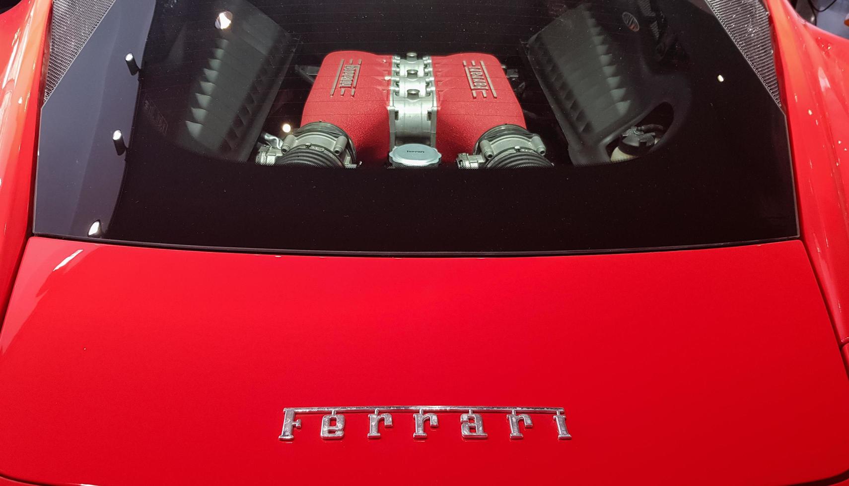 A red Ferrari engine is parked in TNP's car, Rama 9 Road. A close-up of the glass cover of a Ferrari engine in a car dealership. Top view of the engine compartment. Ukraine, Kiev - October 16, 2020. photo