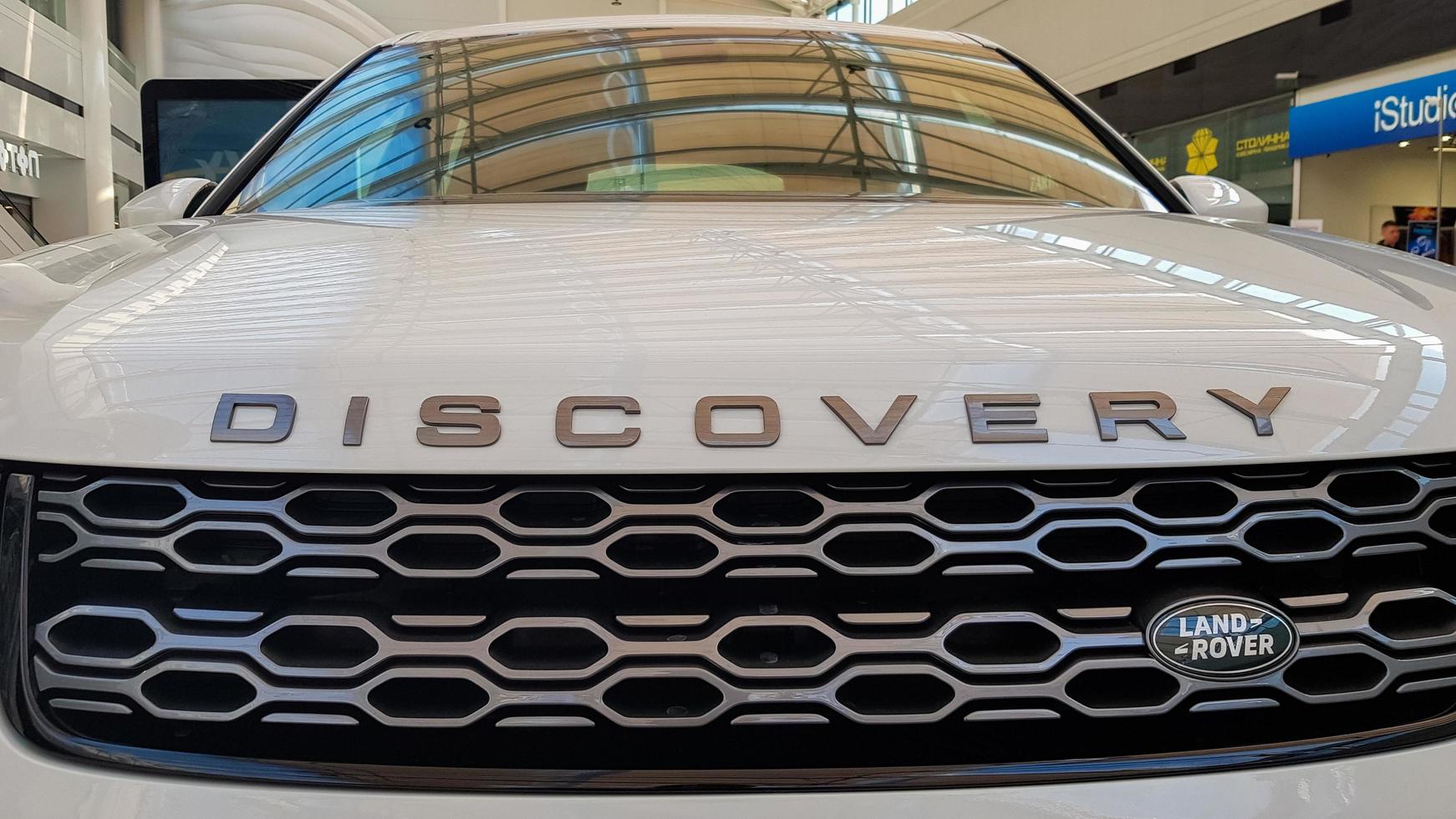 Ukraine, Kiev - March 27, 2020. Land Rover Discovery Sport shiny modern white car at the exhibition. Body, headlights close-up, rear and front view, chrome grille, car logo. photo