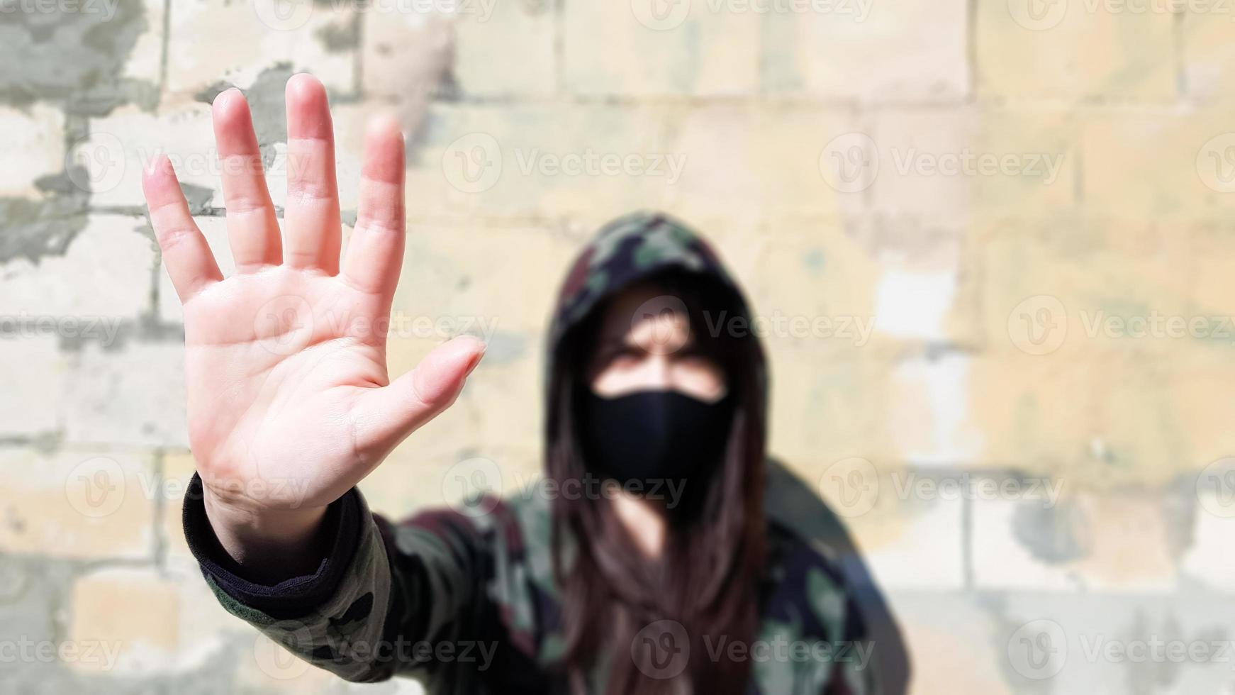 Coronavirus and air pollution concept. The girl wears a protective mask to protect against coronavirus and shows a stop hand gesture to stop the outbreak of the corona virus. photo