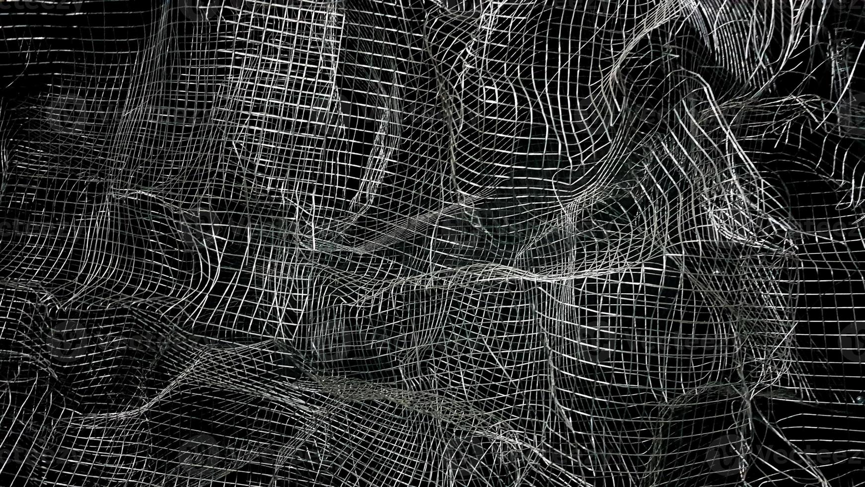Crumpled mesh. Abstract background. Metal mesh with shadow on a black background. The surface of a large roll is damaged by wire mesh. photo