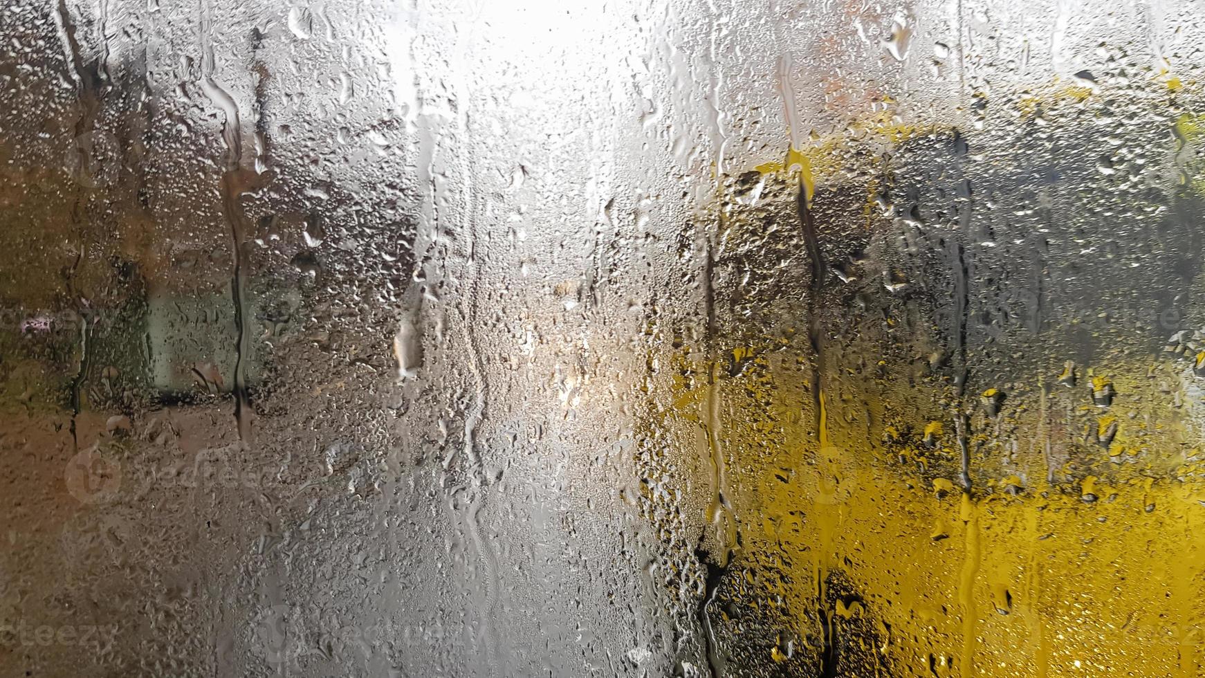 Rain on the rear window of a car in autumn. Inside view of the road with moving cars in the city through the window from the car with rain drops. driving a car in the field of view of the rear window. photo