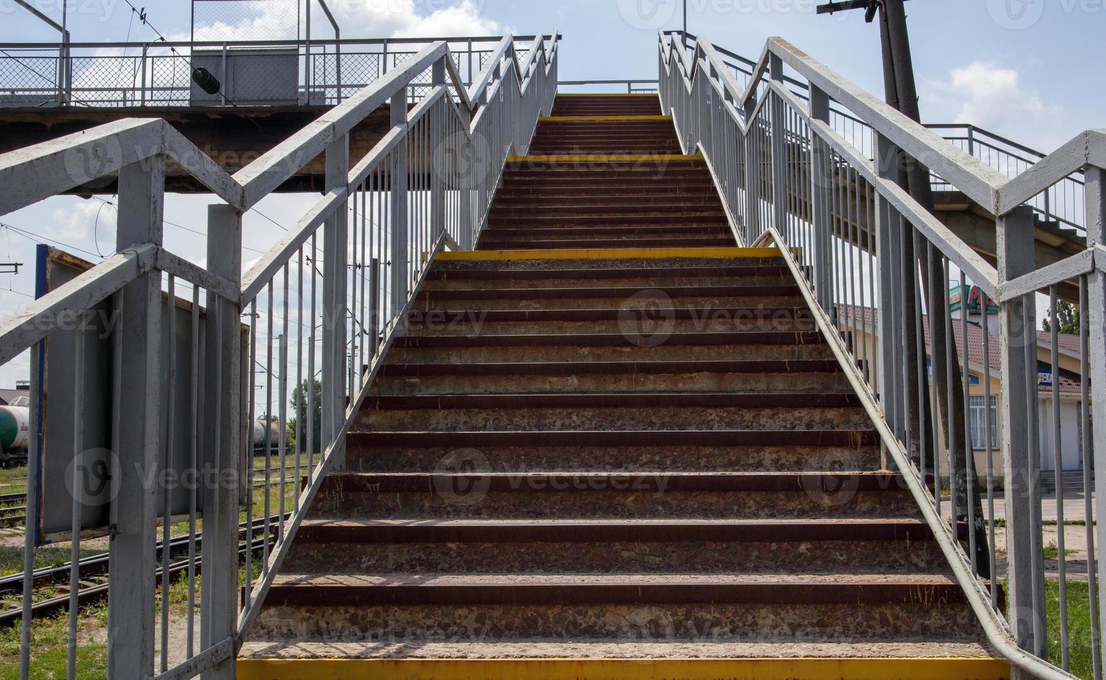 Puente ferroviario con escalones, con impresionantes escalones en perspectiva. Paso de peatones elevado. Puente de escaleras que conectan un andén con otro en la estación de tren. foto