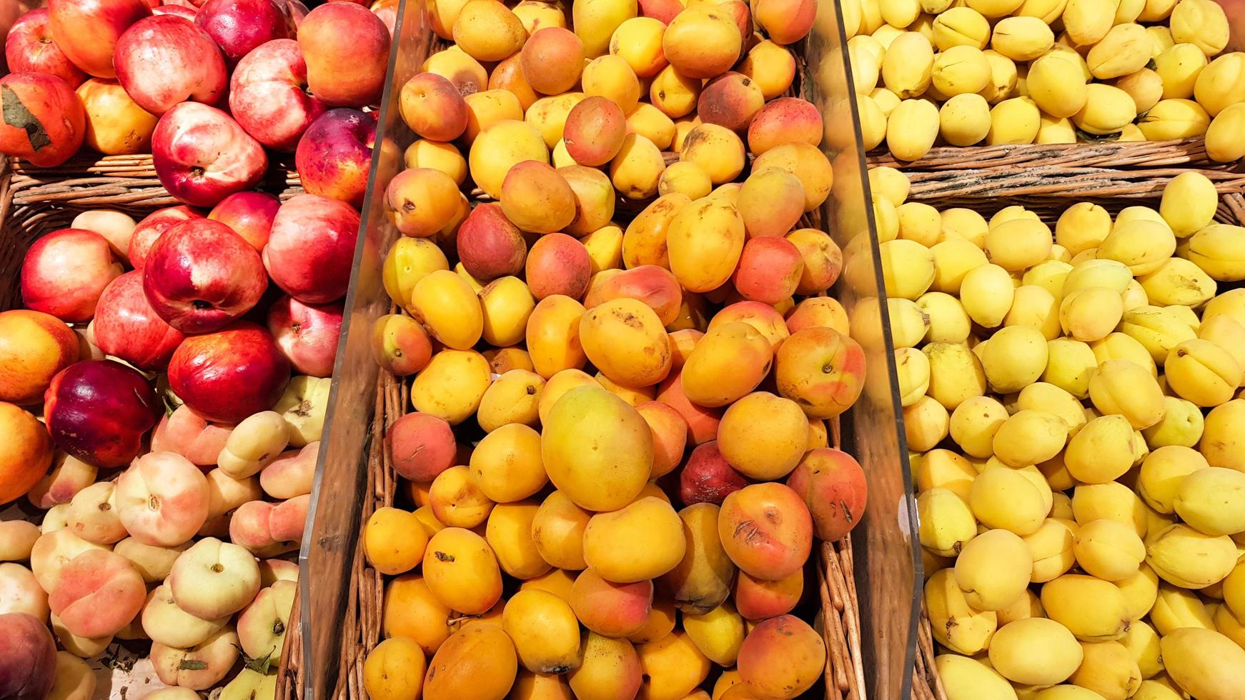 muchas cajas de frutas a la venta en el mercado de frutas. albaricoque y melocotón en un escaparate foto