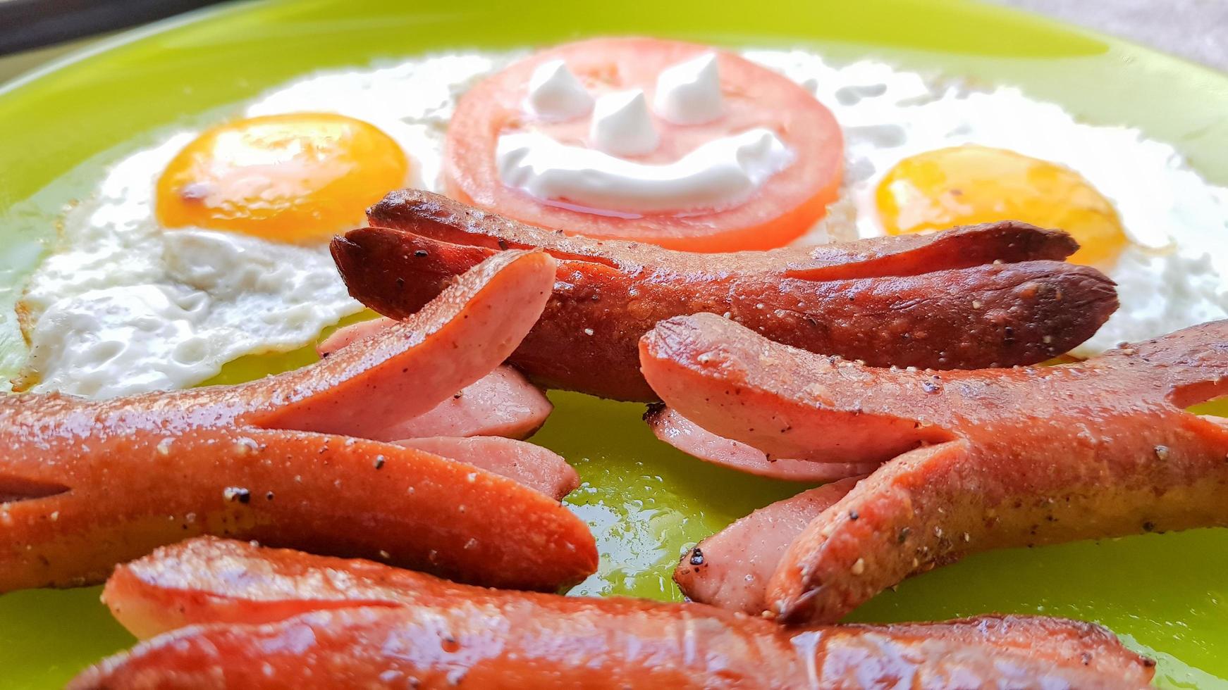 Top view of fried egg and sausages on a green plate, serving breakfast for the baby photo