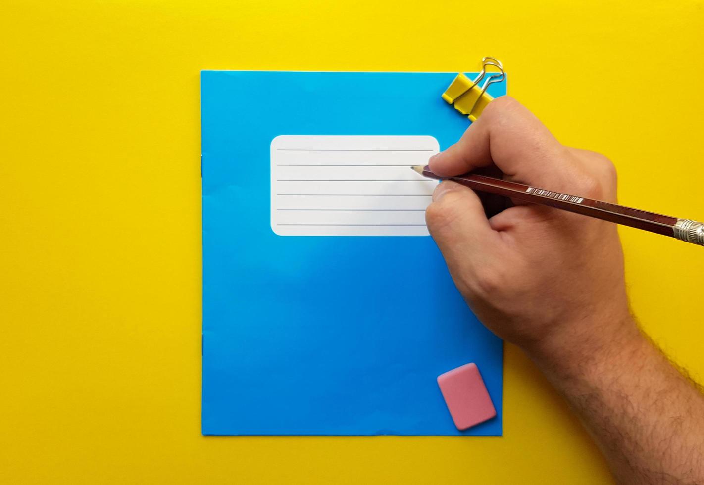 Blue mock up notebook and textbook butt for school subjects, eraser, pencil, paper clip on a yellow background. Flat lay, copy space, top view, place for text. photo