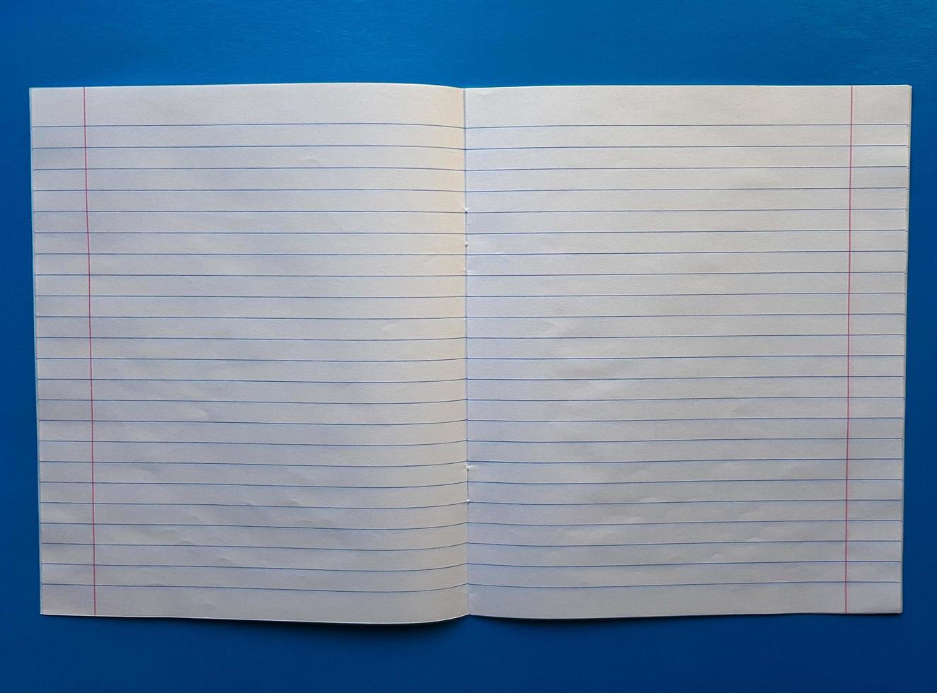 Open notebook on a white lining on a blue wooden tabletop photo