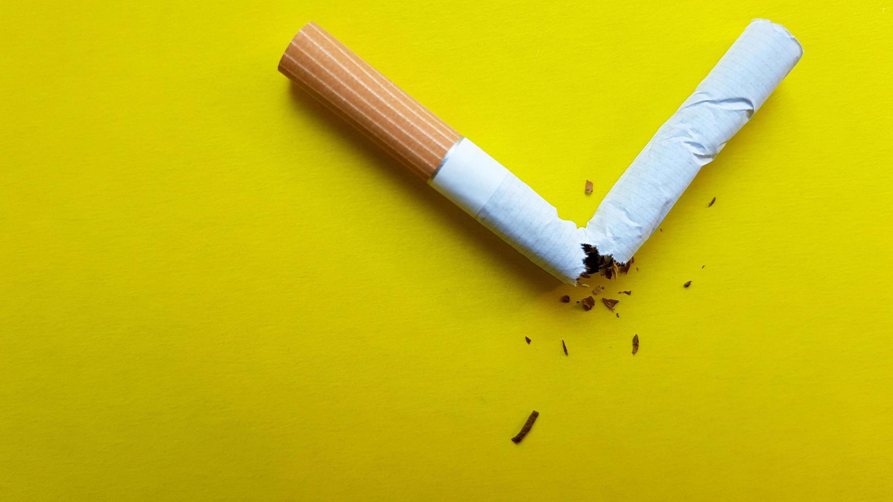 Broken cigarette isolated on a yellow background. View from above photo