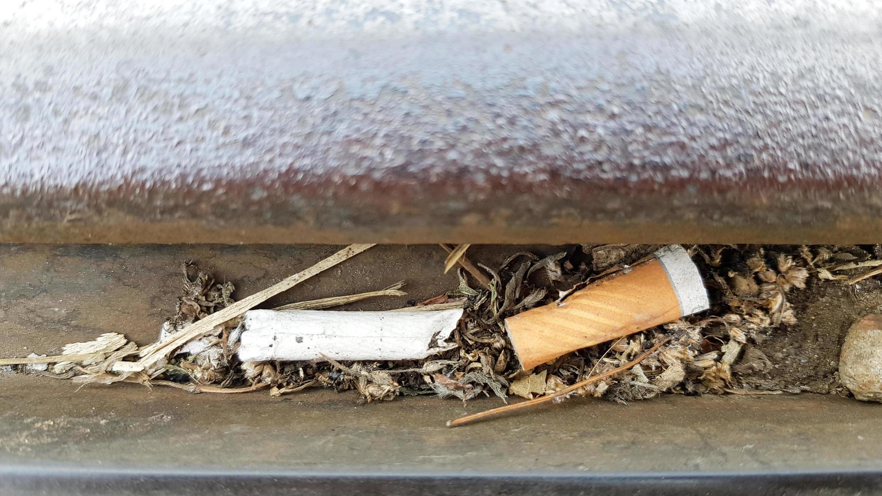 Cigarette butts between two metal sheets in the open lie like garbage photo
