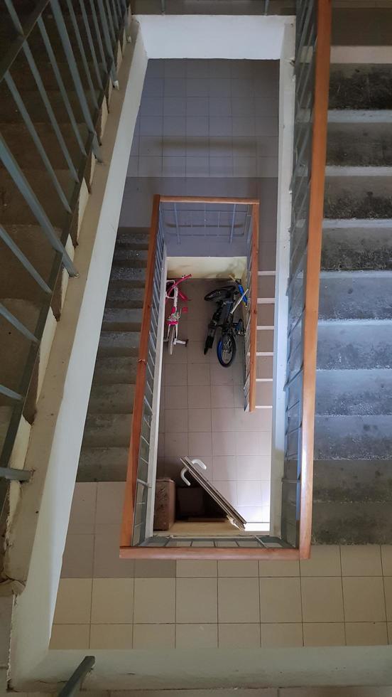 Modern stairwell in a residential building. Staircase in perspective. Gray ceramic tile. Common staircase with a brown wooden fence and concrete steps. View from above. photo