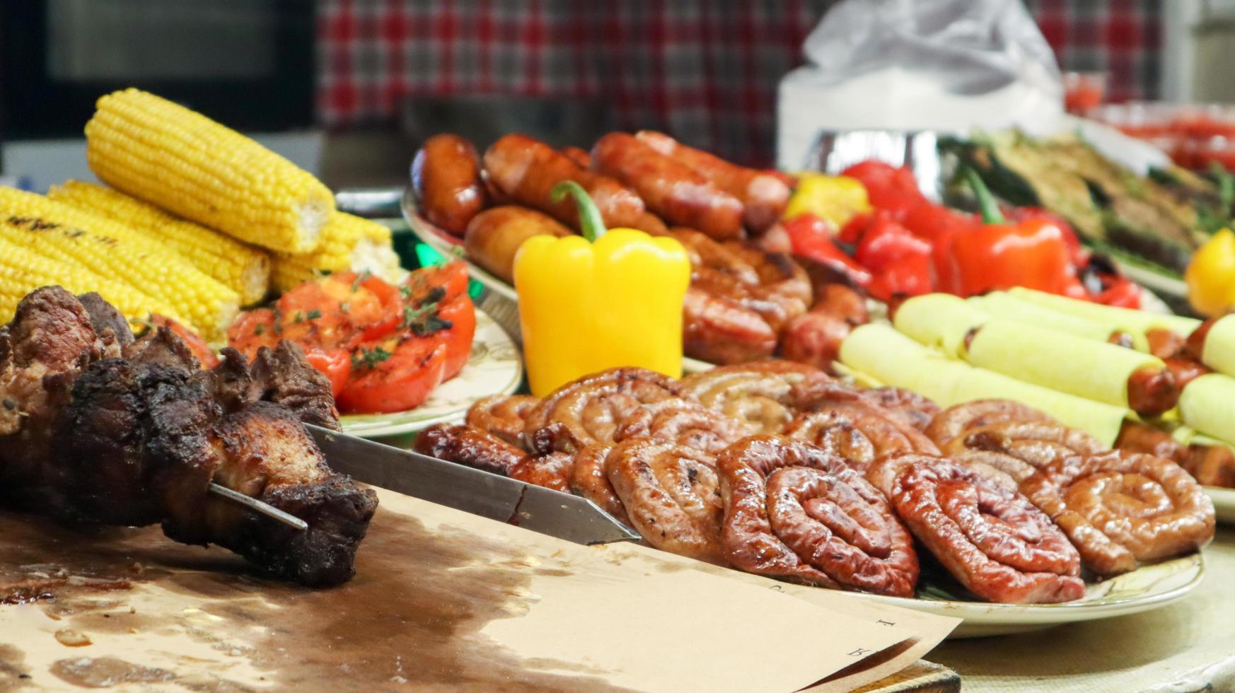 un mostrador con bandejas que contienen salchichas a la parrilla y carne. escaparate redondo de la comida de la calle de la salchicha de la barbacoa. salchichas redondas recién asadas en un festival de comida callejera. una variedad de delicias de carne foto