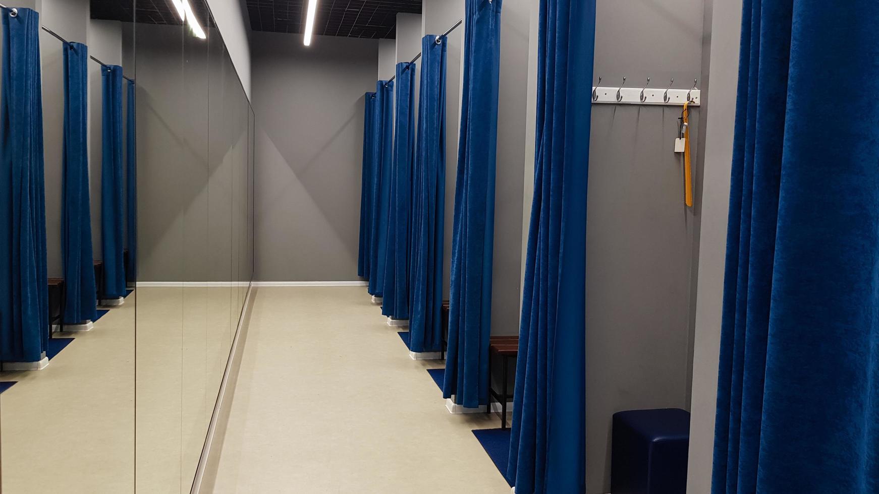Boutique interior, fitting room in a shopping center. Nobody. Empty fitting rooms with blue curtains and gray walls and a large mirror. Dressing rooms in a clothing store without people. photo