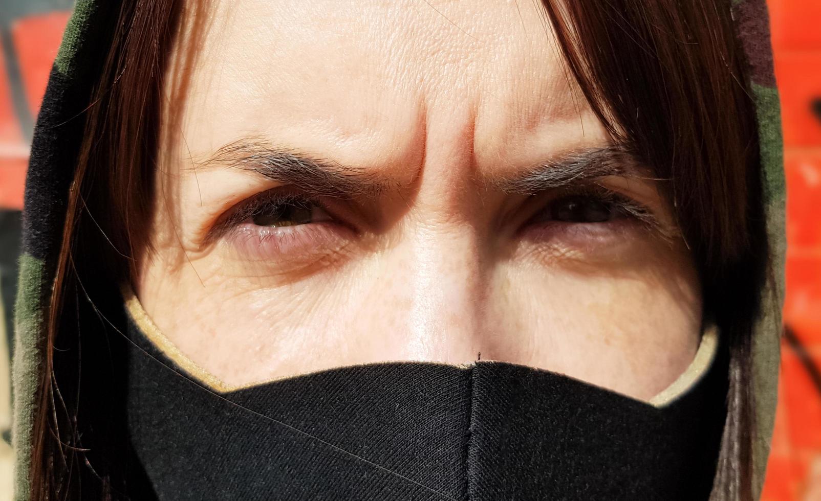 Portrait of a woman in a protective black mask outdoors near an old broken wall. Coronavirus and air pollution concept. A girl wears a protective mask to protect against a pandemic. photo