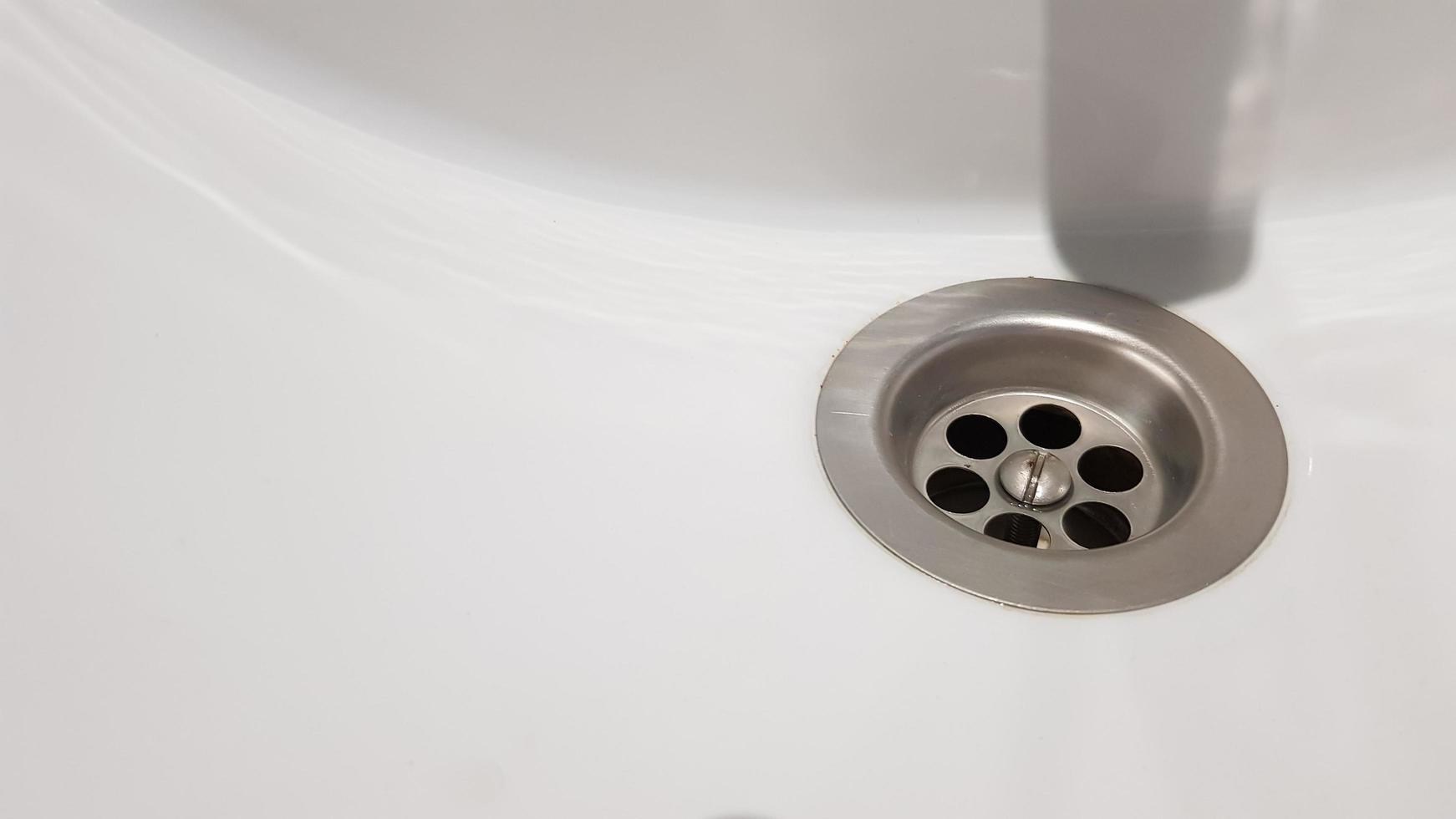 Lavabo de cerámica blanca con grifo cromado en el inodoro con baldosas grises foto