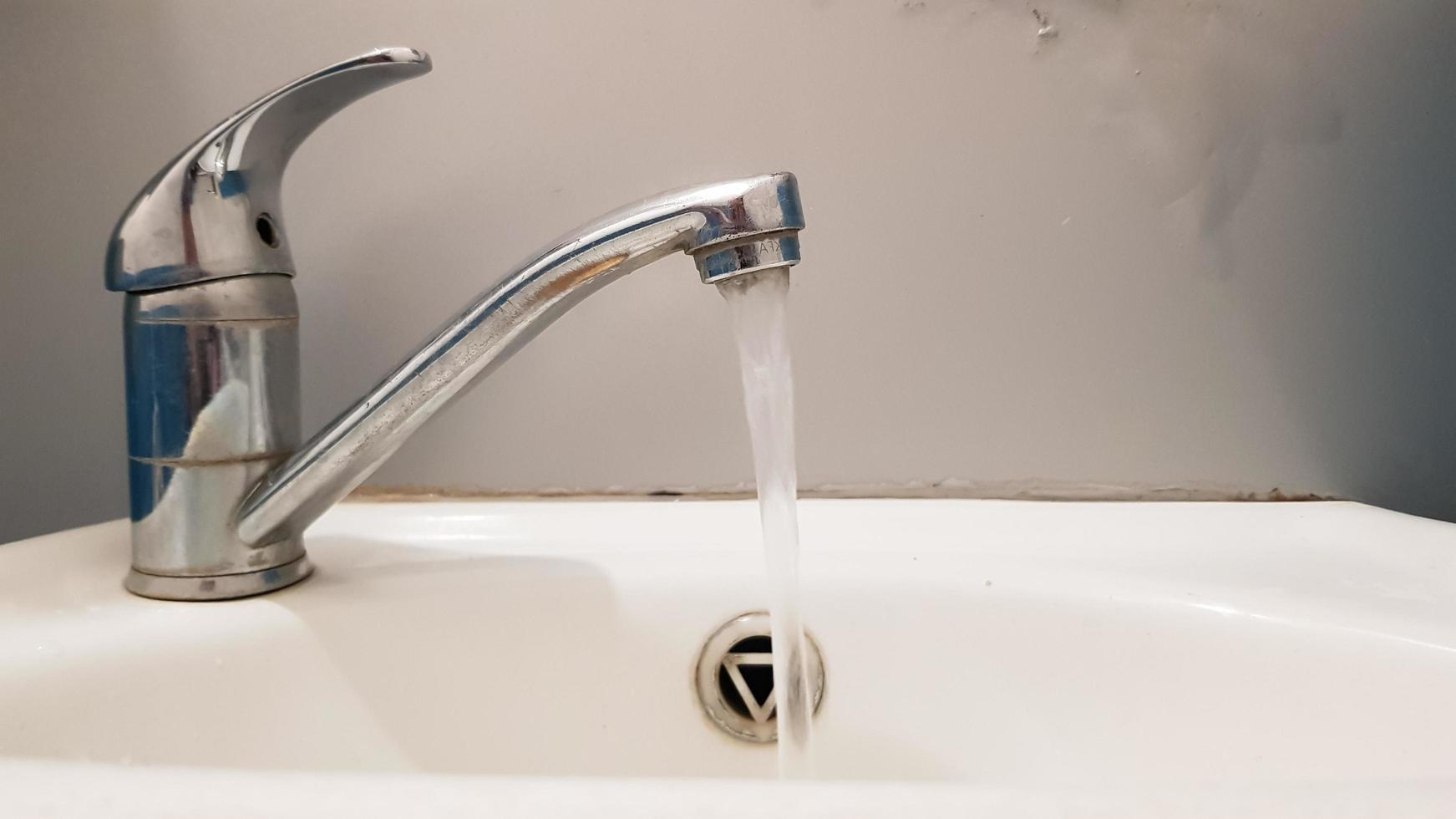 Old and dirty faucet and white ceramic washbasin sink, concept of cleaning, repairing or replacing a bathroom, toilet. photo