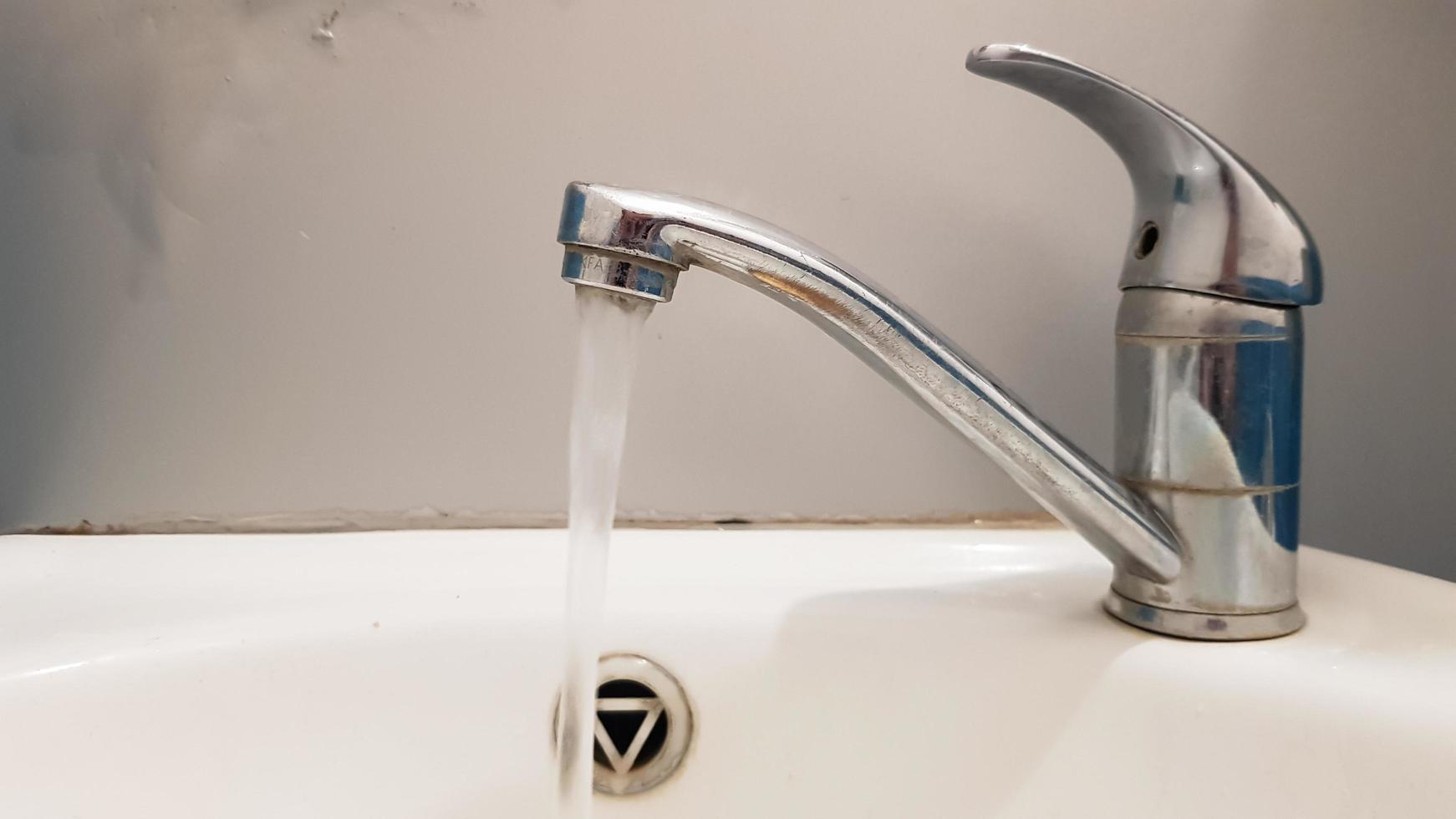 Old and dirty faucet and white ceramic washbasin sink, concept of cleaning, repairing or replacing a bathroom, toilet. photo