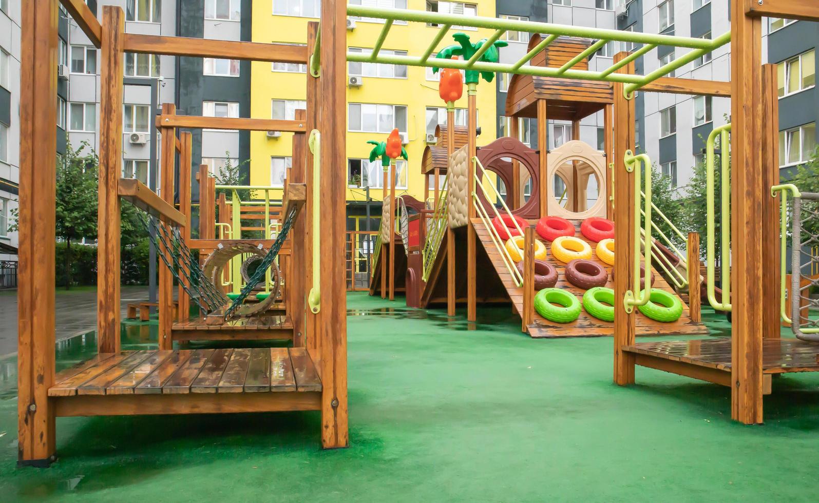 The courtyard of a high-rise building with a modern large playground made of wood and plastic on a rainy summer day without people. Ukraine, Kiev - August 19, 2021. photo