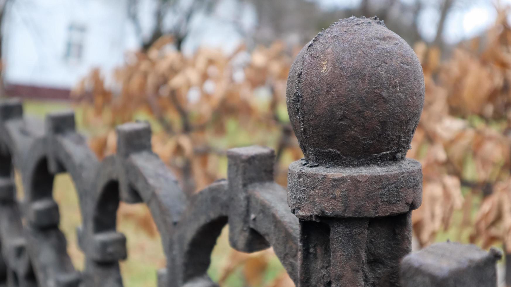 Fragment of a cast-iron fence close-up. An old cast-iron wrought-iron fence with artistic forging against the background of an autumn city park. Selective focus. photo