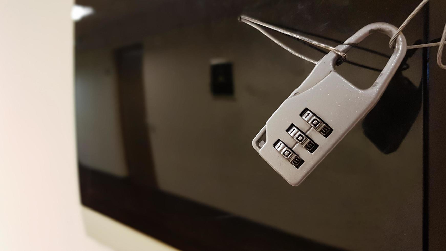 Close-up small combination lock closes electrical panel with black glass cover in office building corridor photo