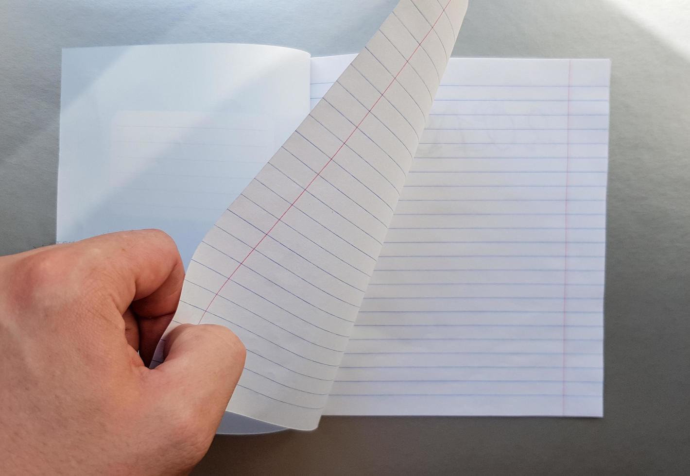 Design concept - Top view of a high quality male hand leafing through a sheet of blue striped notebook. Top view, copy space, flat lay photo