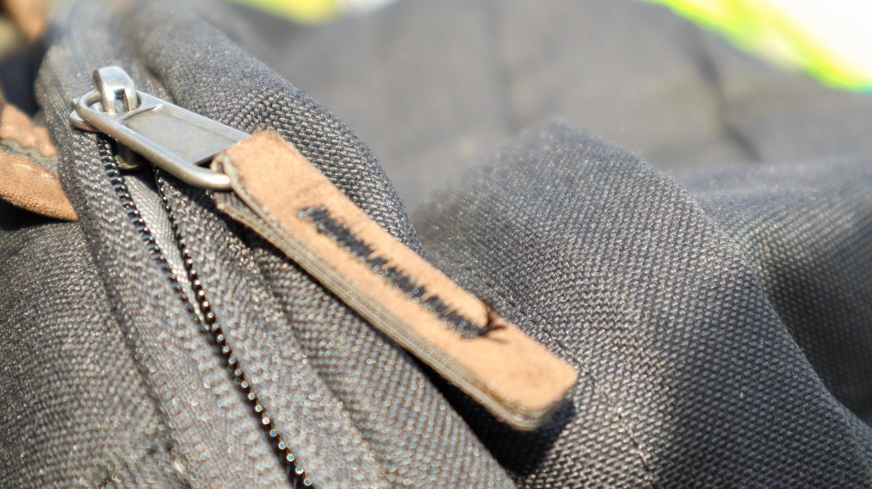 Zipper black bag backpack textile accessories. Close-up view of the clasp. Textile, metal and brown leather. photo