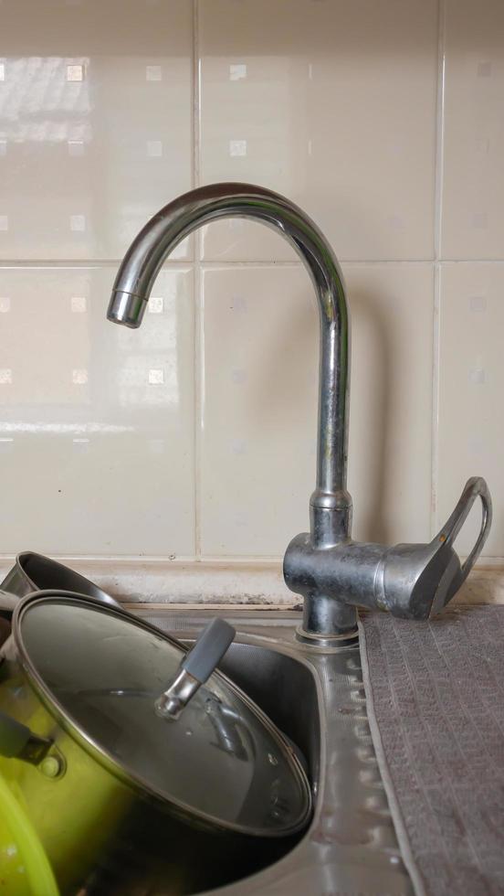 The kitchen utensils in the wash basin need to be washed. A pile of dirty dishes in the kitchen sink. Kitchen utensils need washing. Homework concept. photo