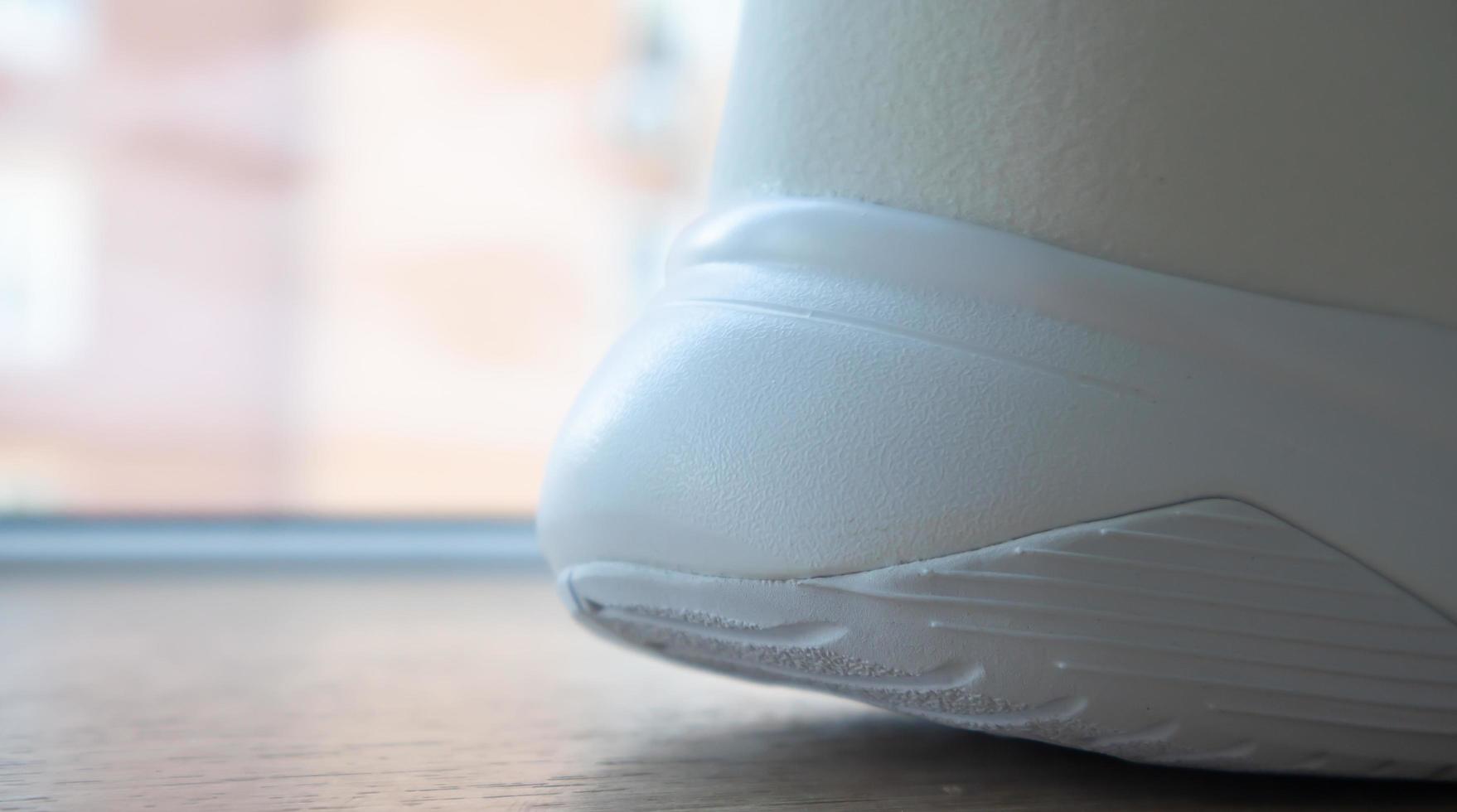Low angle view of the outsole of the back of new white sneakers. Rubber sole on the heel of men's shoes. Sole for sports and walking shoes. Material texture of sports shoes. photo