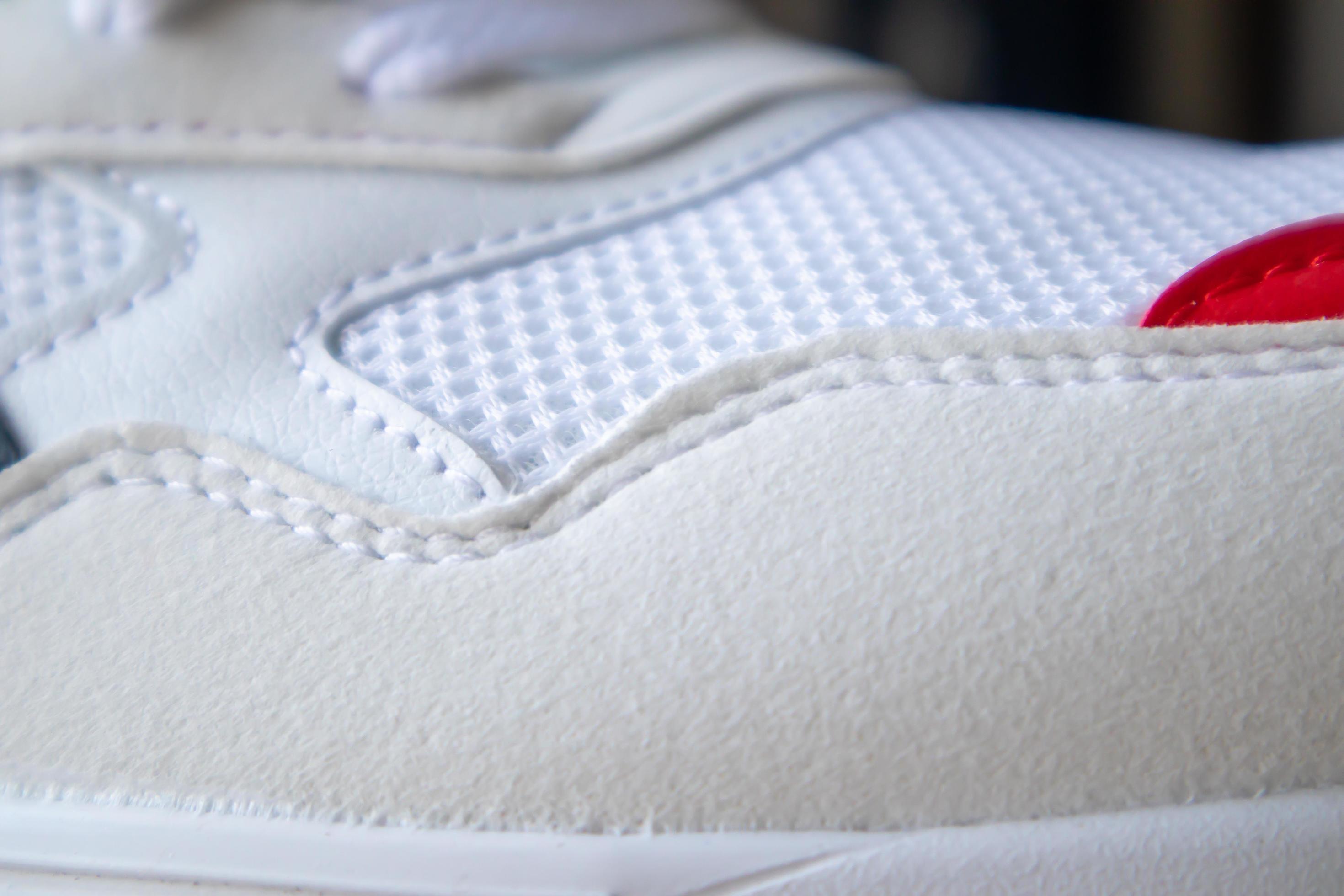 White color mesh fabric on a part of sports shoes. Running shoe net. Sportswear textured lattice. Textile texture background. Detail of a white sneaker in fabric with laces. Fragment of sports shoes