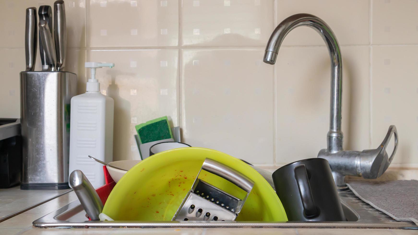The kitchen utensils in the wash basin need to be washed. A pile of dirty dishes in the kitchen sink. Kitchen utensils need washing. Homework concept. photo