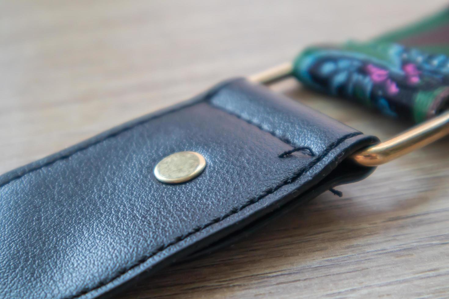 Detail of a fashionable black leather handbag close-up. Fashion concept. Details of a belt, metal buckle, fastener, sewing threads, macro photography. Stylish female accessory. photo