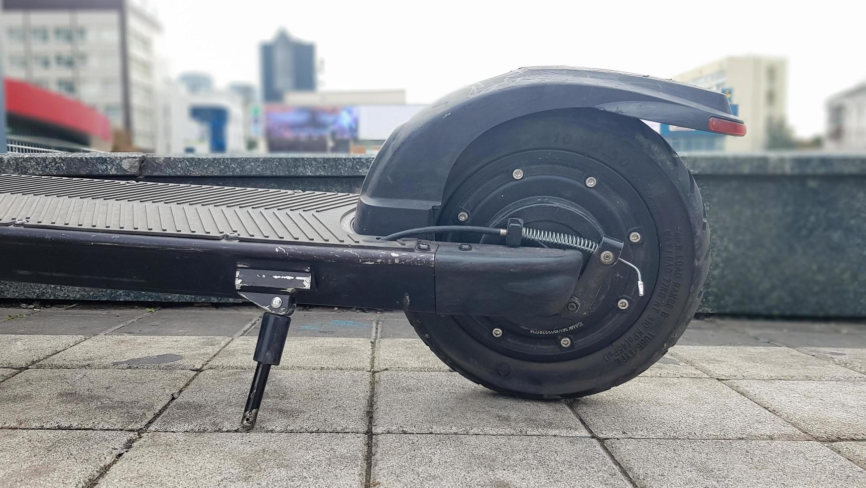 The rear wheel of an electric scooter on a city street against the background of paving slabs. Old e-scooter wheel. Eco transport is provided for rent. Ukraine, Kiev - October 17, 2020. photo