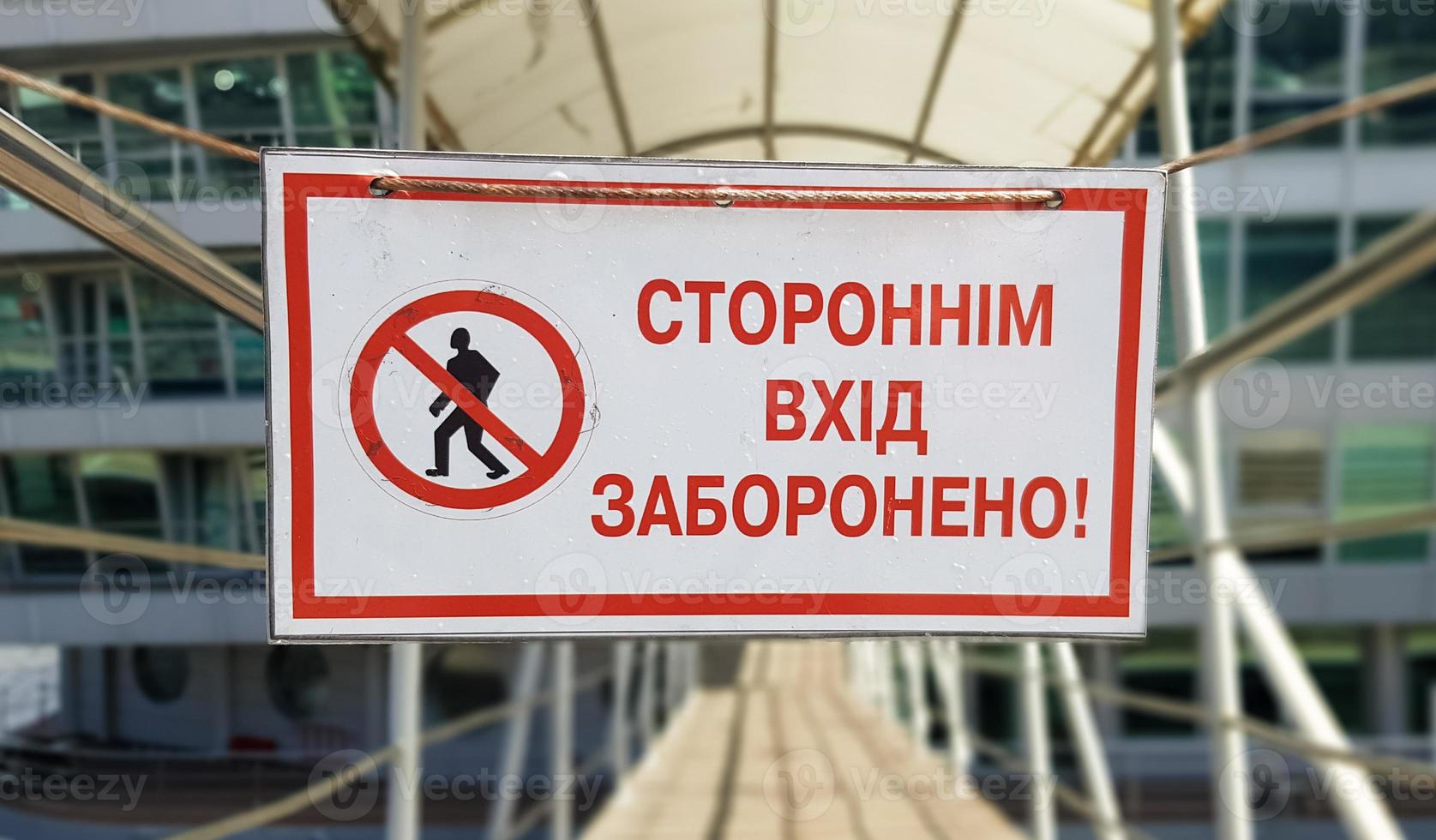 Warning sign No unauthorized entry written in red text in Ukrainian on a white rectangular table. The sign prohibits the passage of strangers. photo