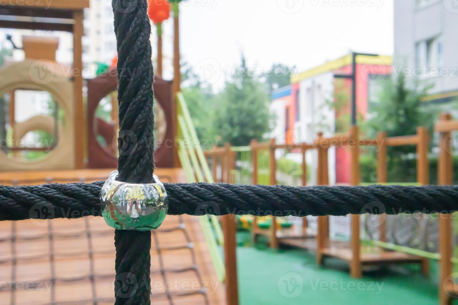 A courtyard of high-rise buildings with a modern and large playground made of wood and plastic on a rainy summer day without people. Empty outdoor playground. A place for children's games and sports. photo
