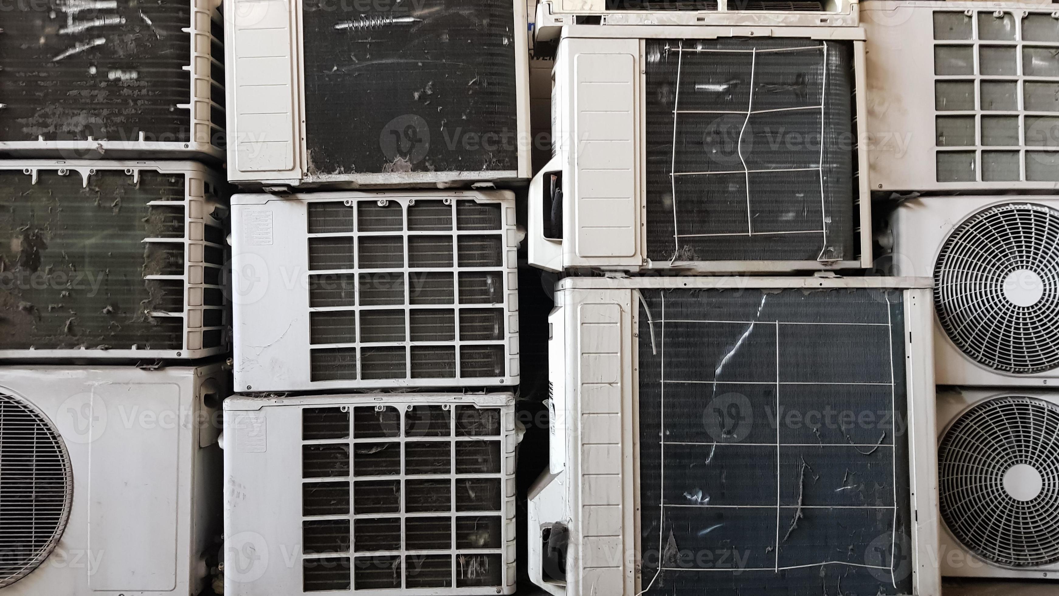 A group of dirty, dusty and broken air conditioning compressors are